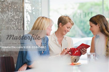 Femme assise avec ses amis dans un restaurant et à la recherche dans son portefeuille