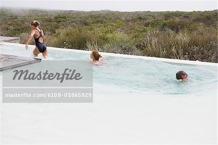 Deux filles, nager dans une piscine à débordement avec un garçon