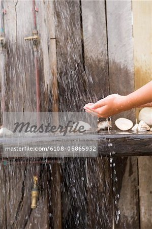 Close-up of a person's hands under a beach shower