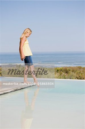 Jeune fille debout sur une plate-forme à une piscine à débordement