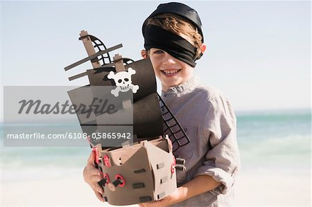 Boy in pirate costume playing with a toy boat