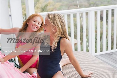 Deux filles, assis sur une balançoire de porche