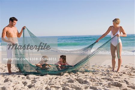 Family playing with a fishing net on the beach