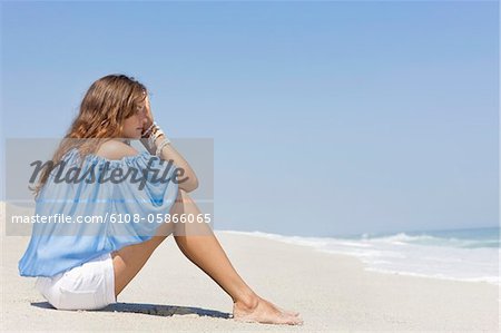 Frau am Strand sitzen und denken