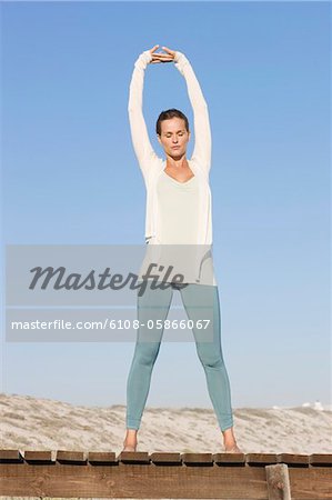 Woman stretching her arms on a boardwalk