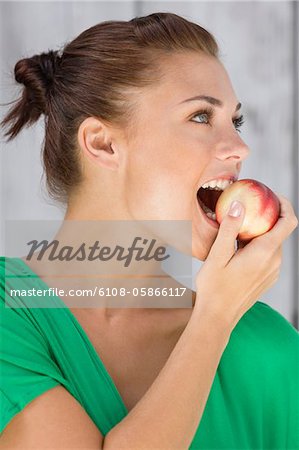 Femme mange une pomme et souriant