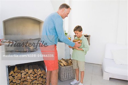 Mann Spiesse im Kamin mit seinem Sohn hält Brennholz Kochen