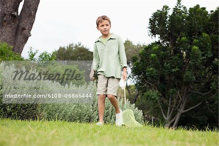 Junge spielt mit einem Schmetterling net in einem Garten