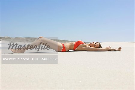 Porträt einer Frau, die am Strand liegen