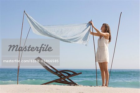 Woman fixing a canopy on the beach