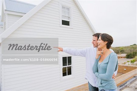 Man pointing towards a house with a woman standing beside her