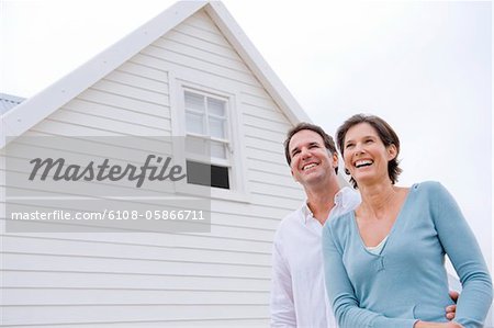 Couple smiling with a house in the background