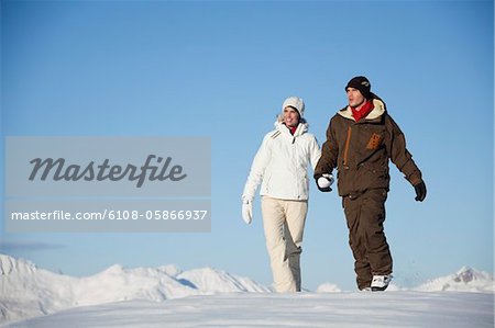 Young couple holding hands, walking in snow