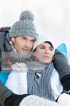 Young couple in winter clothes, listening to music together