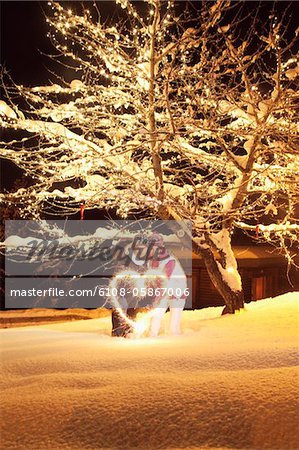 Young couple making heart shape with sparkler by night