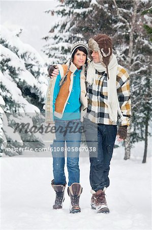 Young couple embracing, walking in snow