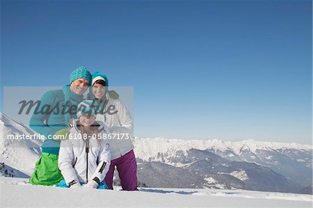 Couple et fille dans des vêtements de ski, souriant à la caméra