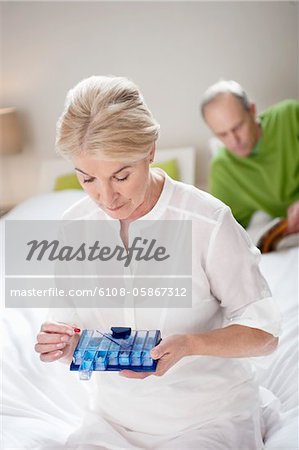 Woman taking a capsule with her husband behind her