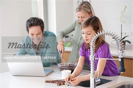 Familie Kochen mit dem Rezept auf einem laptop