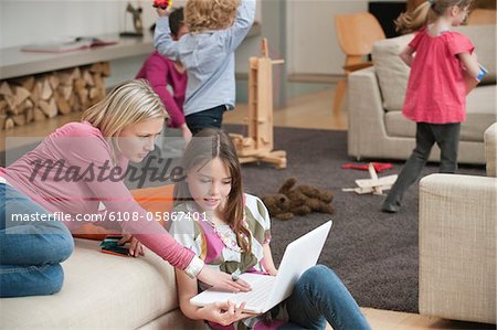 Woman assisting her daughter in using a laptop