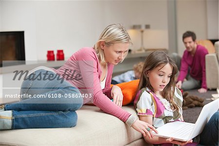 Woman assisting her daughter in using a laptop