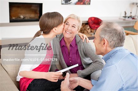 Jeune fille embrasser sa grand-mère avec son grand-père, assis à côté d'eux