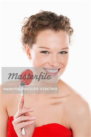 Porträt einer Frau, die eine Tomate auf eine Gabel halten