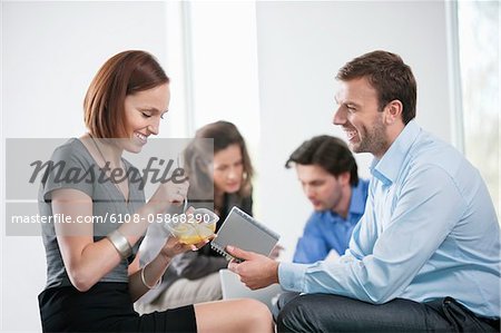 Woman eating food with their colleagues sitting with her
