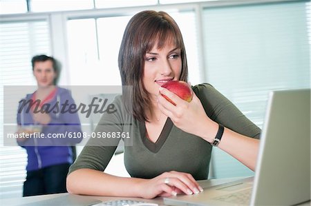 Femme d'affaires, manger une pomme et à l'aide d'un ordinateur portable