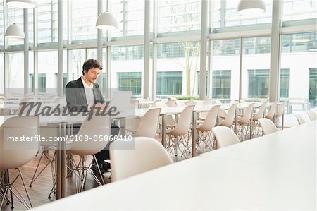 Businessman sitting at a cafeteria and using a laptop