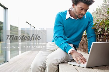 Homme utilisant un ordinateur portable sur un trottoir de bois