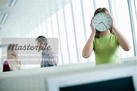 Geschäftsfrau hält eine Uhr vor ihrem Gesicht