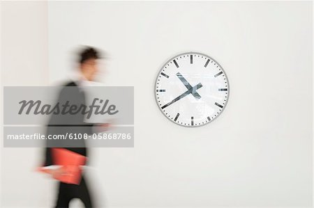 Businessman walking in front of a clock