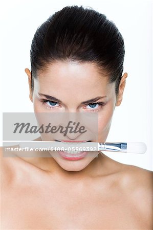 Young woman biting make-up brush