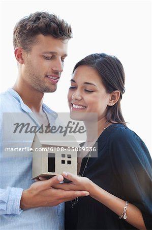 Cute young couple holding small model house