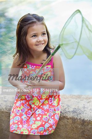 Petite fille assis près de la piscine avec filet à la main