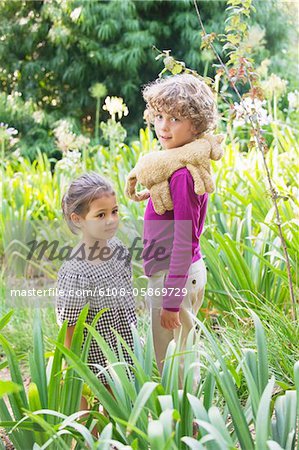 Portrait of a smiling boy standing with little girl in a garden