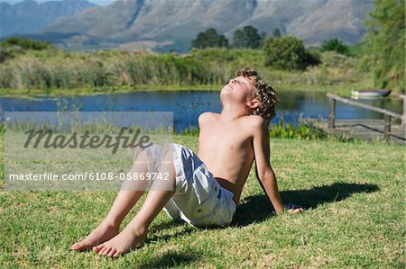 Shirtless little boy sitting with his eyes closed against mountain