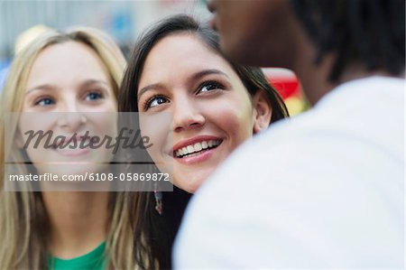 Two women looking at a man and smiling
