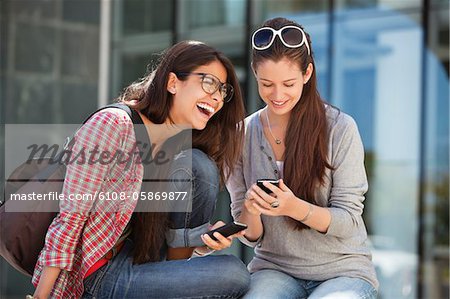 Zwei Freundinnen, die Benutzung von Mobiltelefonen