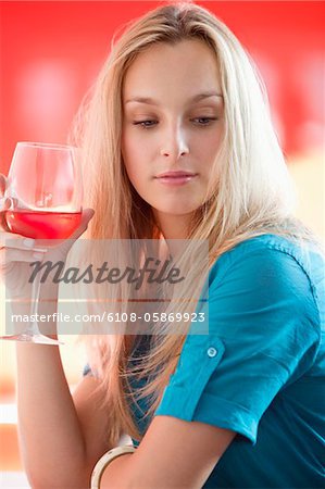 Young woman having red wine and thinking in a bar