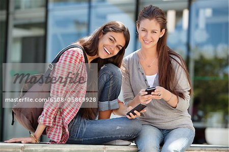 Portrait de deux femmes tenant le téléphone mobile et souriant