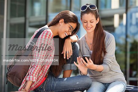 Two female friends reading text message on a mobile phone
