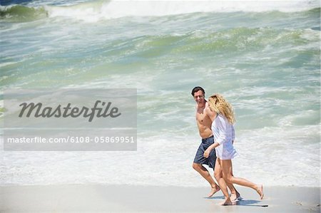 Side profile of a couple running on the beach