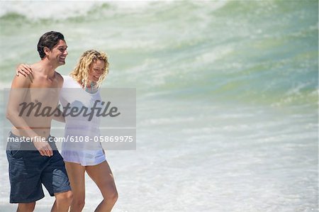 Couple walking on the beach with their arms around each other