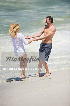 Mid couple adulte jouant sur la plage