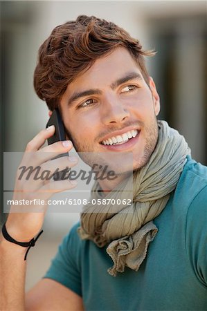 Jeune homme de parler sur un téléphone mobile