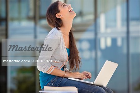 Woman laughing while using a laptop