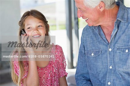 Fille parlant sur un téléphone mobile avec son grand-père près d'elle