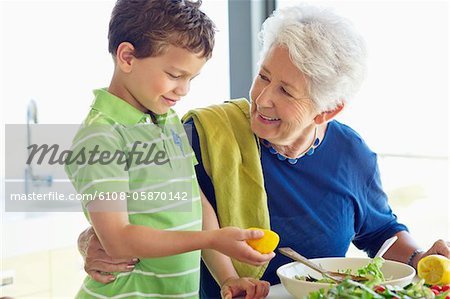 Senior woman preparing food in a kitchen with her grandson